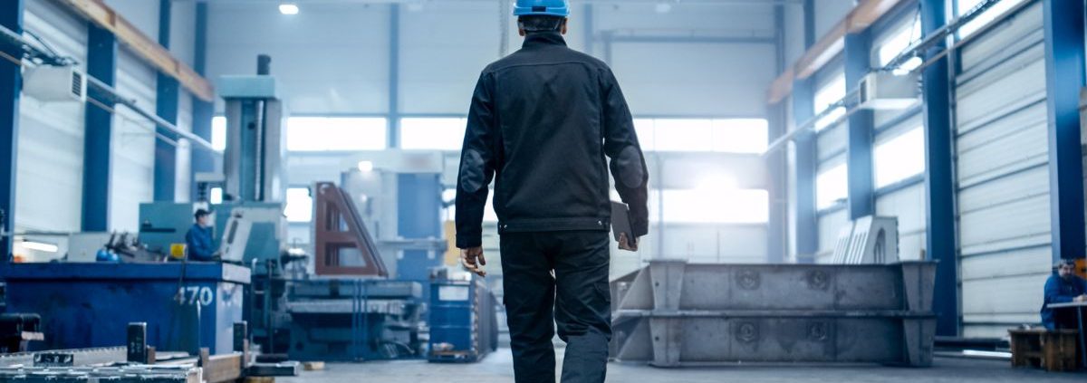 man in a factory wearing a hard hat and holding a clipboard - Innovative Garage Flooring commercial flooring solutions