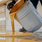 InnovativeGarageFlooring-polyaspartic-floor-coatings-032020251 person pouring yellow liquid onto a floor - Innovative Garage Flooring polyaspartic floor coating